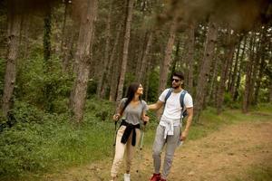 Couple of hikers with backpacks walk through the forest photo