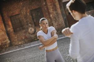 Young woman doing stretching exercise after jogging with her personal trainer photo