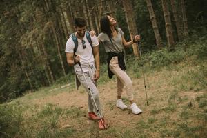 Couple of hikers with backpacks walk through the forest photo