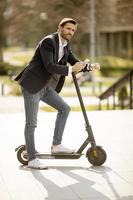 Young businessman using mobile phone  on electric scooter photo