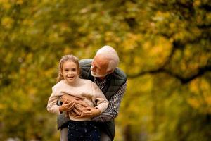 Grandfather spending time with his granddaughter in park on autumn day photo