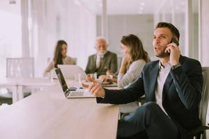 Young business man using mobile phone in the office photo