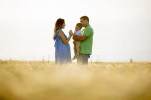 Familia joven con lindo niño divirtiéndose al aire libre en el campo foto