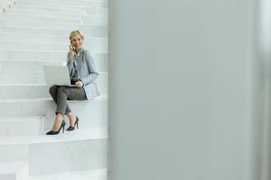 Businesswoman using mobile phone on modern office stairs photo