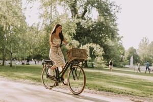 mujer joven con bicicleta eléctrica y flores en la cesta foto