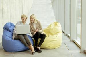 mujeres de negocios que usan computadoras portátiles en bolsas perezosas en la oficina moderna foto