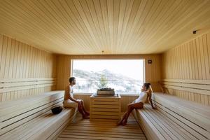 pareja joven relajándose en la sauna y viendo el bosque de invierno a través de la ventana foto