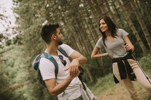 Couple of hikers with backpacks walk through the forest photo