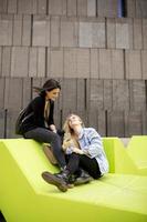 mujeres jóvenes sentadas en la ciudad y usan un teléfono móvil foto