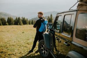 Young man relaxing by the terrain vehicle hood at countryside photo