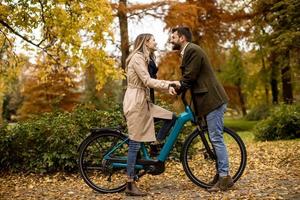 pareja joven, en, el, otoño, parque, con, bicicleta eléctrica foto