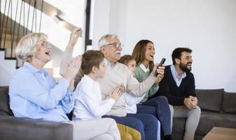 Multi generation family sitting together on the sofa at home and watching TV photo