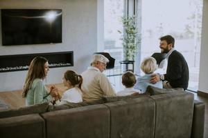 familia multigeneracional sentada en el sofá de casa y viendo la televisión foto