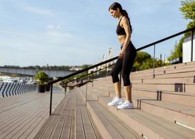 Young woman in sportswear exercising on a river promenade photo