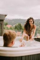 Young couple enjoying in outdoor hot tub on vacation photo