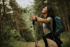 Young female backpacker woman enjoying green beautiful forest around her photo