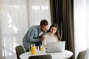 Young couple using laptop computer on the table in the living room photo