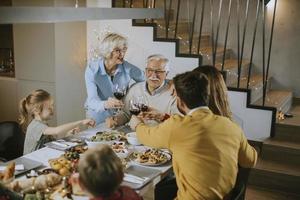 familia feliz cenando con vino tinto en casa foto