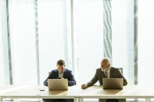 Businesspeople sitting and working in laptops at the office photo