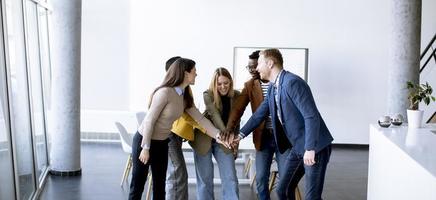 Young creative team putting their hands together in the modern office photo