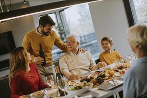 Young man poring red wine to his father for testing during at home photo