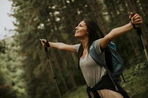 Young female backpacker woman enjoying green beautiful forest around her photo