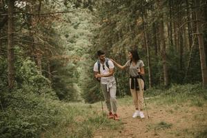 Couple of hikers with backpacks walk through the forest photo