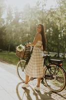 mujer joven con flores en la cesta de la bicicleta eléctrica foto