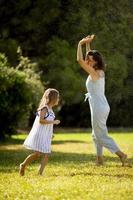 Cute little girl having fun under irrigation sprinkler with her mother photo