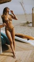 Mujer joven en bikini de pie junto al bar de la playa en un día de verano foto