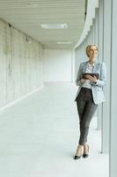 Businesswoman using digital tablet on modern office hallway photo