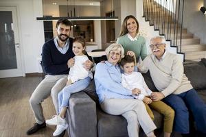 familia multigeneracional sentada en el sofá de casa foto