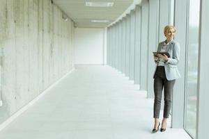 Businesswoman using digital tablet on modern office hallway photo