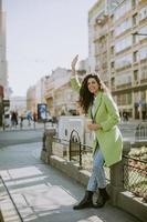 mujer joven en la calle con café para llevar foto