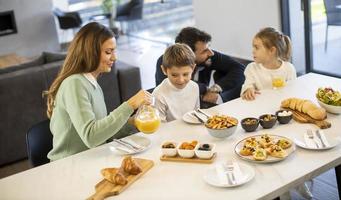 Young happy family talking while having breakfast at dining table photo