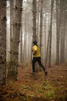 Young man running in autumn forest and exercising for trail run marathon endurance race photo
