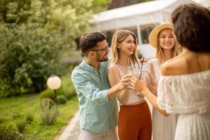 grupo de jóvenes felices animando con limonada fresca en el jardín foto