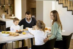 Young happy family talking while having breakfast at dining table photo