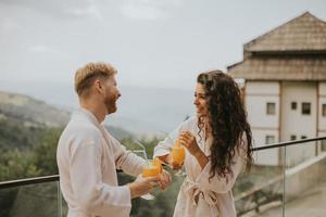 pareja joven relajándose en la terraza al aire libre y bebiendo jugo de naranja fresco foto