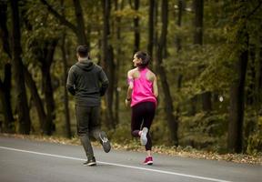 Athletic couple running together on the forest trail photo