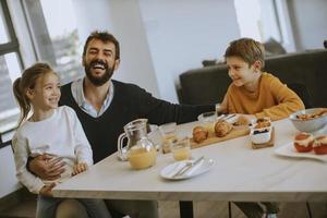 Father having breakfast with his son and daughter at home photo