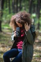 Teen girl with retro camera taking photos in nature