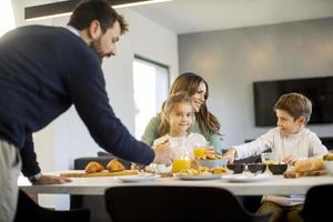 Young happy family talking while having breakfast at dining table photo