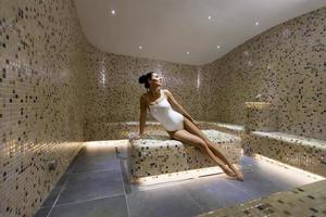 Young woman relaxing on the tepidarium bed in the spa photo