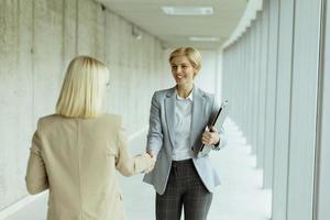 Business women handshaking in the office corridor photo