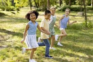 grupo de niños asiáticos y caucásicos divirtiéndose en el parque foto