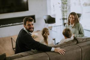 Young family watching TV together on the sofa in the living room photo