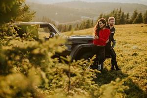 Smiling couple preparing hiking adventure with backpacks by terrain vehicle photo