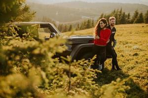 Smiling couple preparing hiking adventure with backpacks by terrain vehicle photo