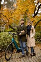 pareja joven, en, el, otoño, parque, con, bicicleta eléctrica foto